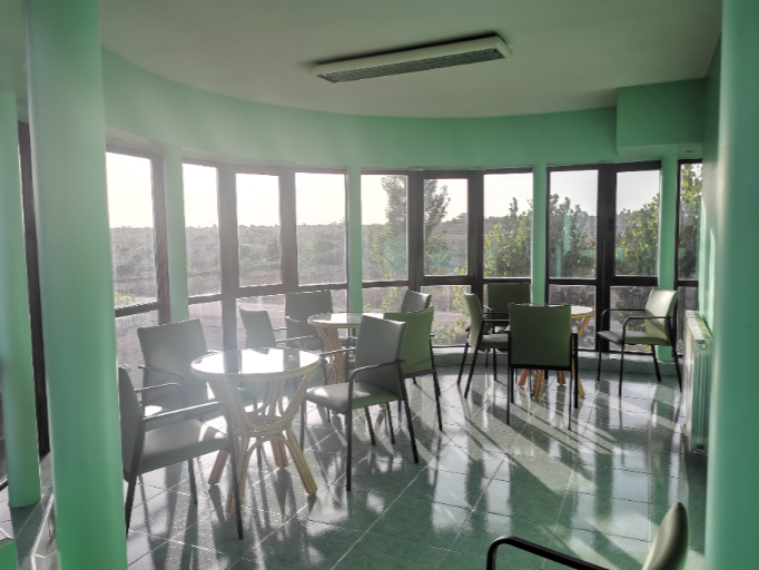 sala de estar con mesas redondas y sillas verdes del centro de Campolar Ardoncino