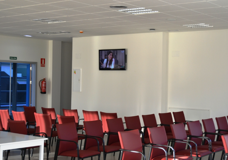 sala de actos con sillas rojas y un televisor de Campolar Bierzo
