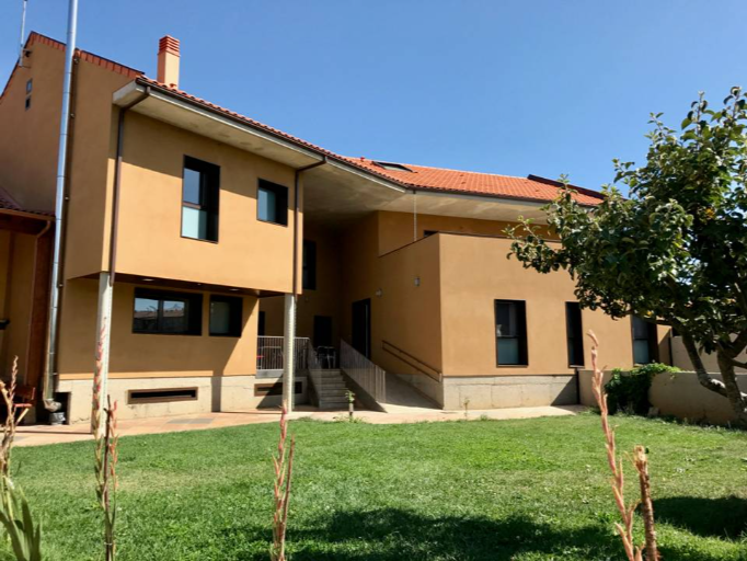 fachada de la casita de color crema con jardín